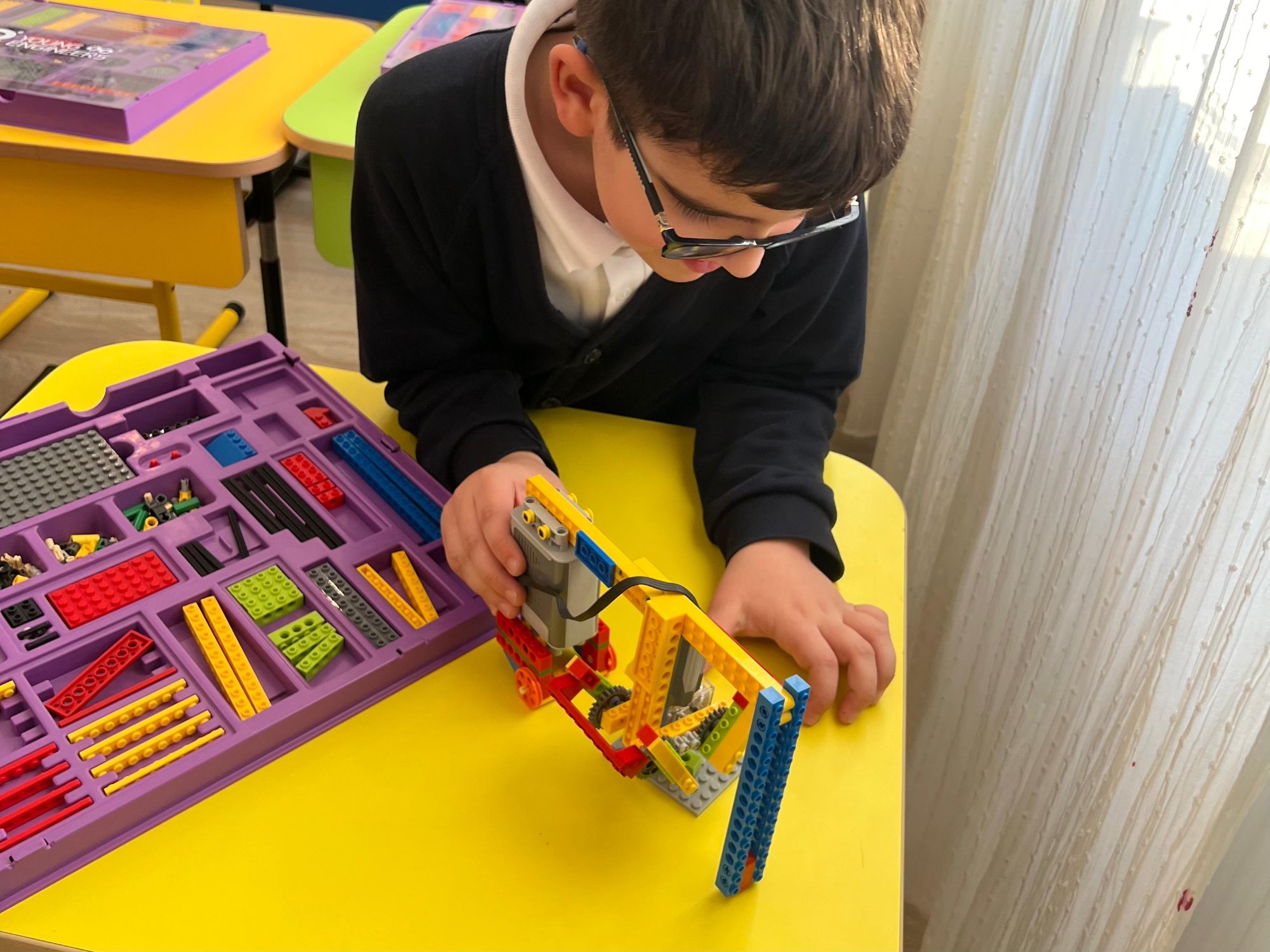 Copil construind mecanism LEGO