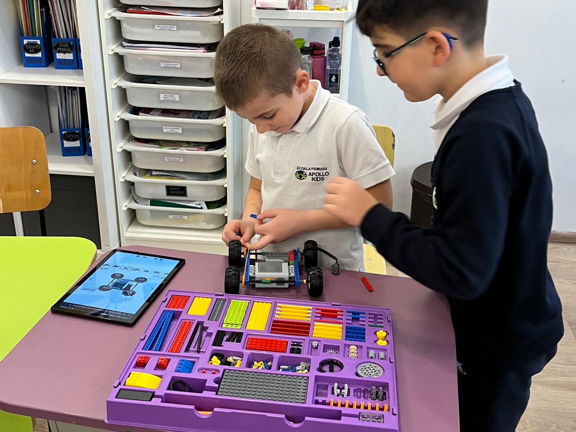 Doi copii lucrând în echipă la robot